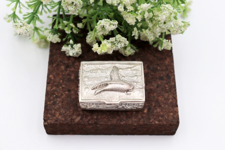 Caixa de comprimidos em prata com ave em alto relevo na tampa